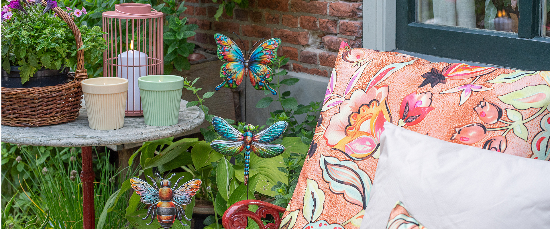 Voorjaarsdecoratie van Anna’s Collection met kleurrijke sierkussens, decoratieve tuinstekers en sfeervolle lantaarns.